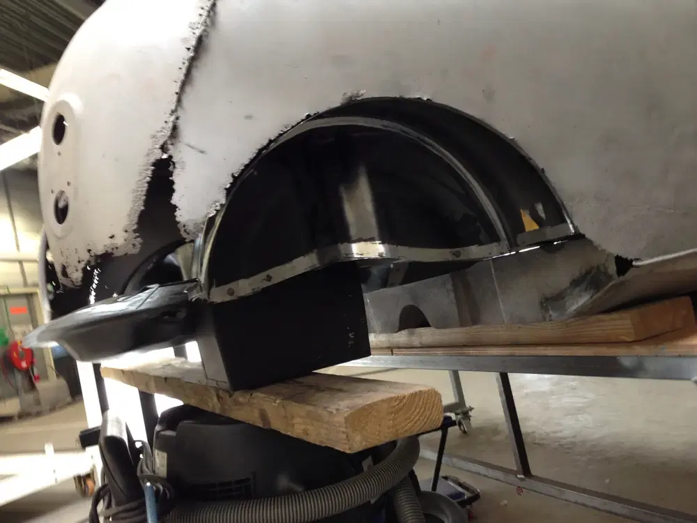 Restauration de carrosserie de voiture sur un établi en bois dans un atelier.