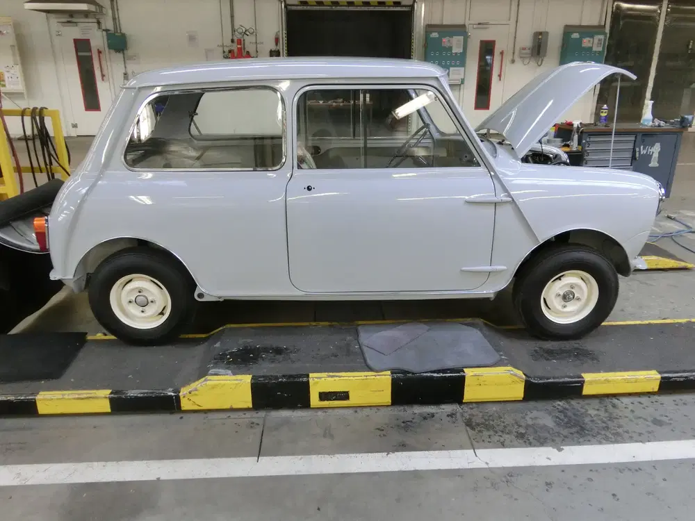 Mini Cooper classique avec capot ouvert dans un atelier de réparation automobile.