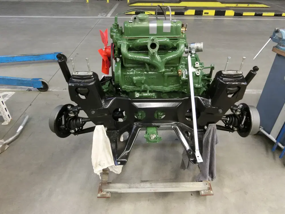 Moteur vert restauré avec châssis noir, atelier automobile en arrière-plan.