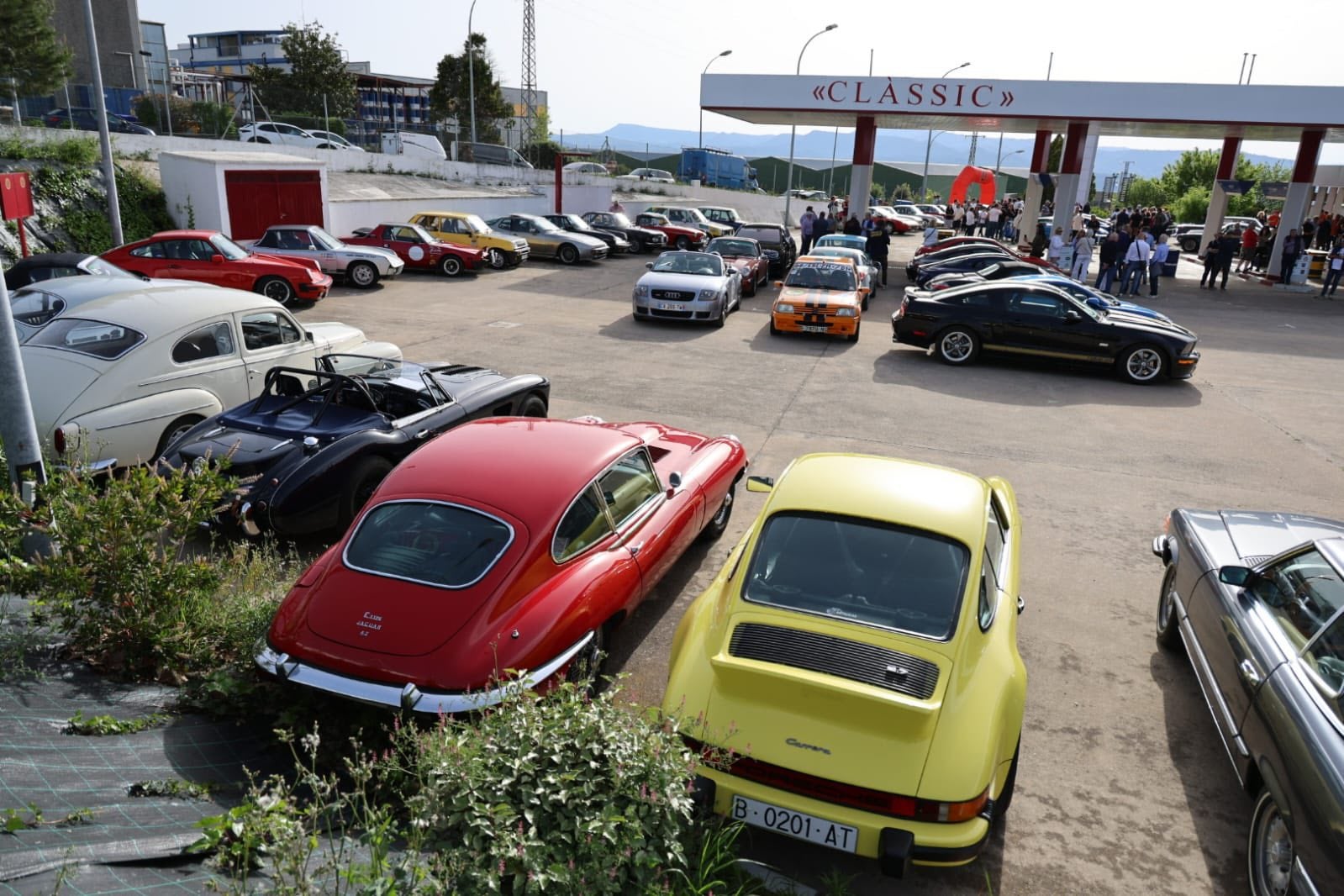 Des voitures anciennes et des participants réunis sur une aire de stationnement avant le Rallye des deux Catalognes 2026.