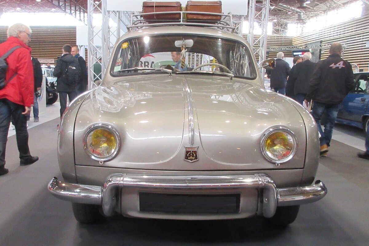 Renault Dauphine de face lors d’un rassemblement de voitures anciennes, galerie de toit chargée de valises d’époque